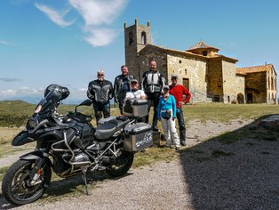 Grupo de motoristas delante de una iglesia románica en los Pirineos.