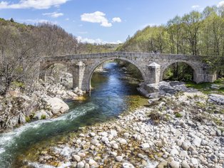 Motociclista en un puente de piedra en España