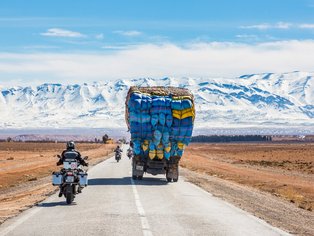 Motoristas en carretera delante de las cumbres nevadas de las montañas del Atlas
